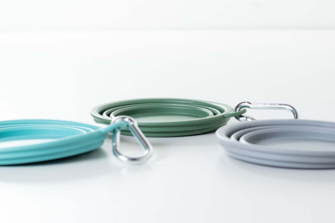 Set of three silicone expandable water bottles in blue, green, and gray on a white background