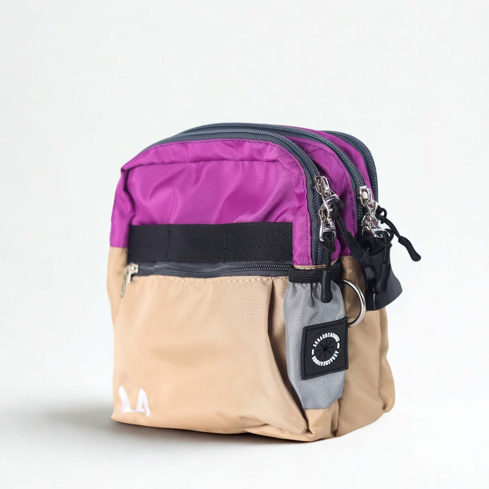 Purple and beige crossbody dog training bag with multiple zippers on a white background