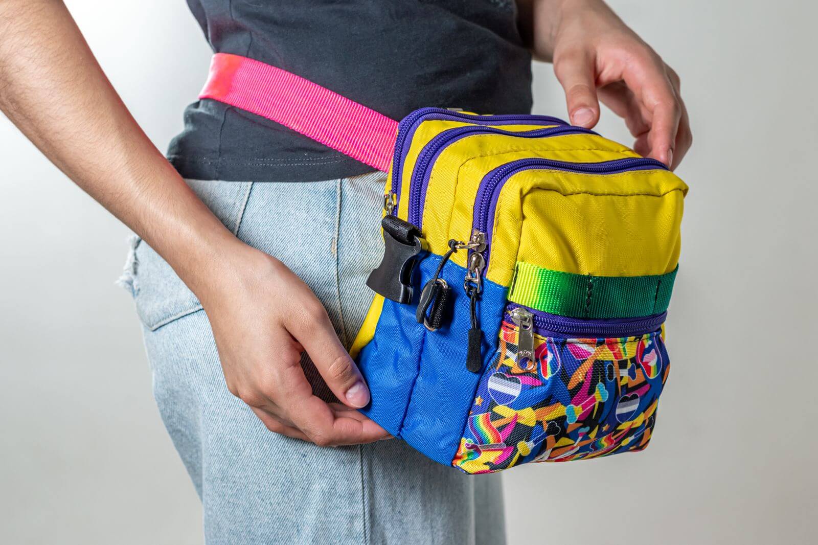 Colorful pride/rainbow crossbody bag used on the waist by a person against a neutral background