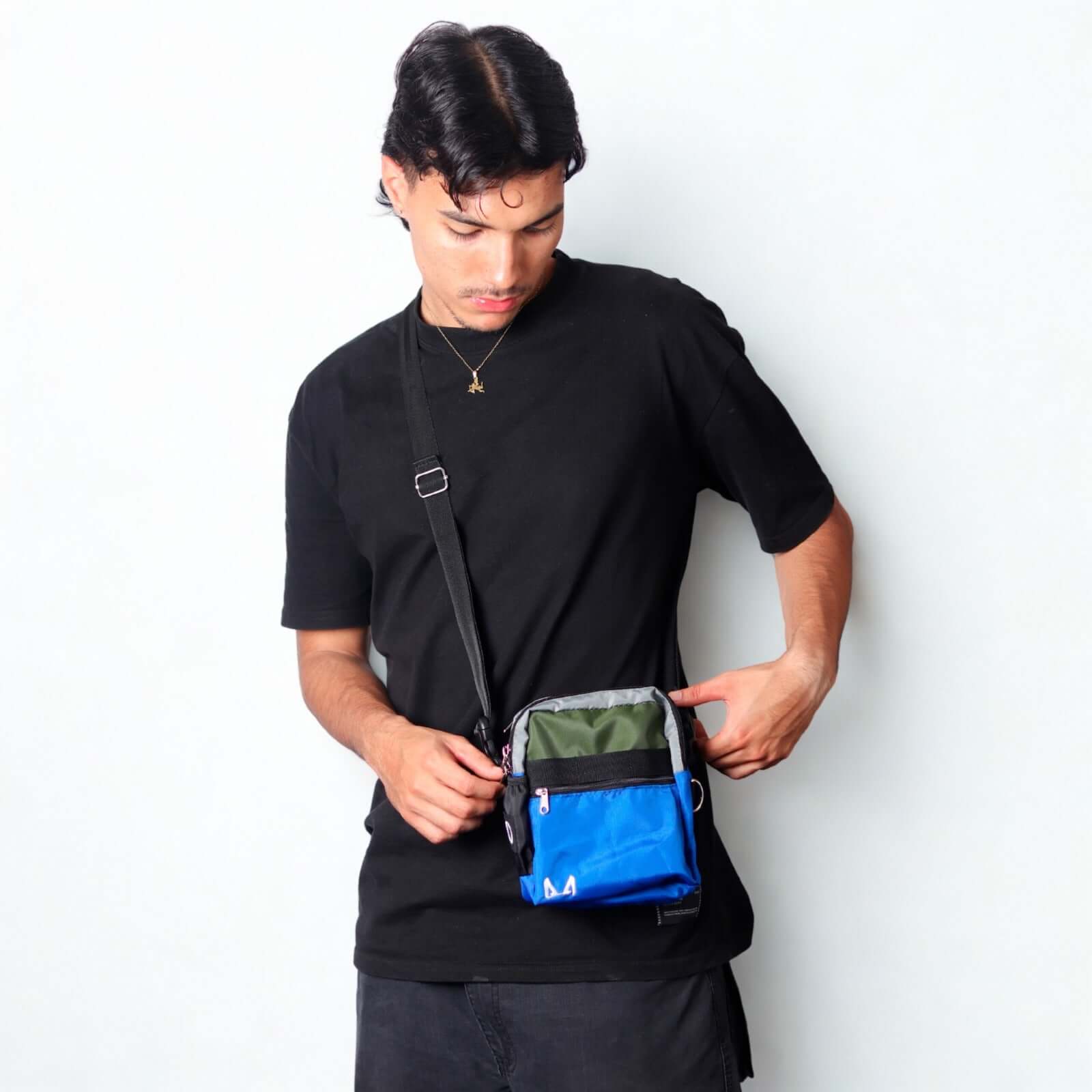 Person wearing a black shirt with a blue and green bag crossbody bag.