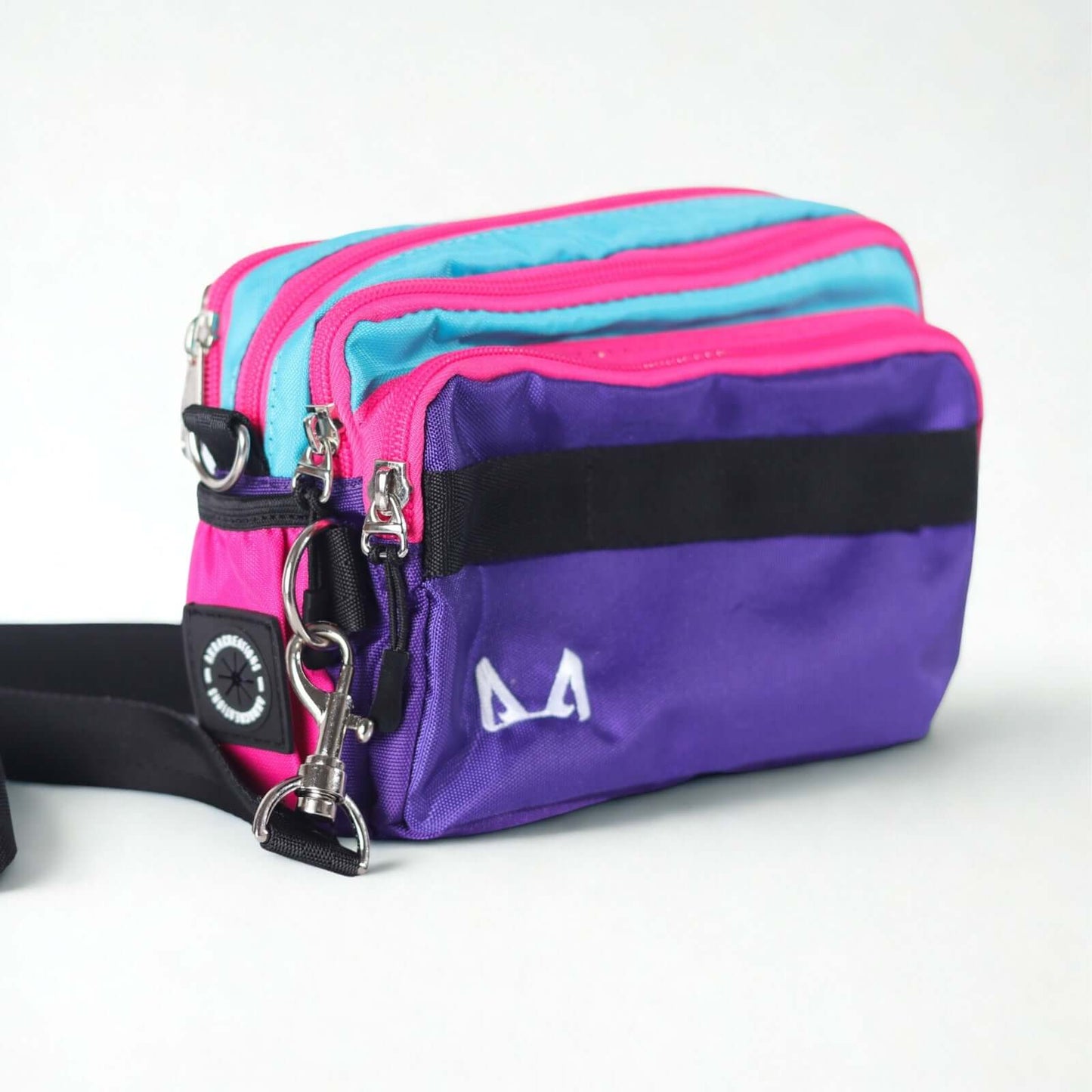 A purple and pink dog training fanny pack with black straps and a logo on the front.