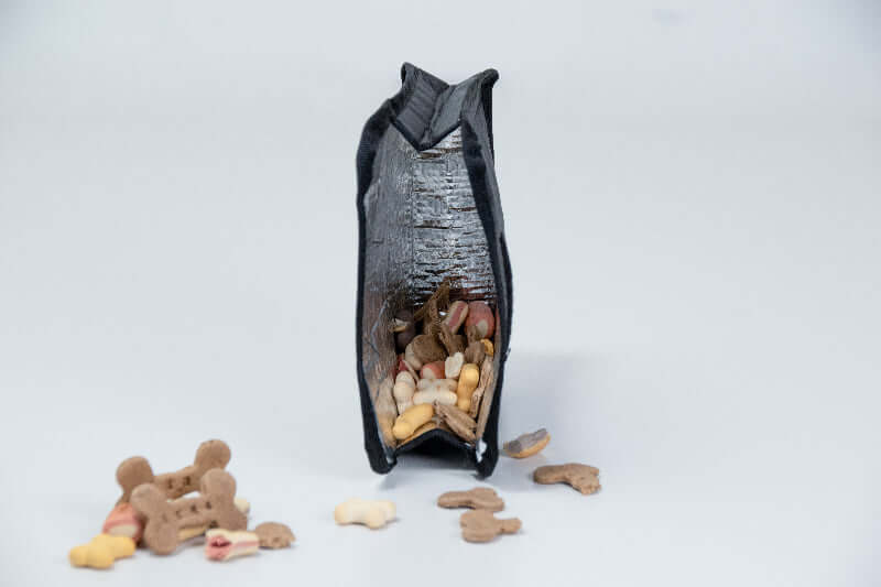 Dog treat insulated sleeve with treats spilling out on a white background