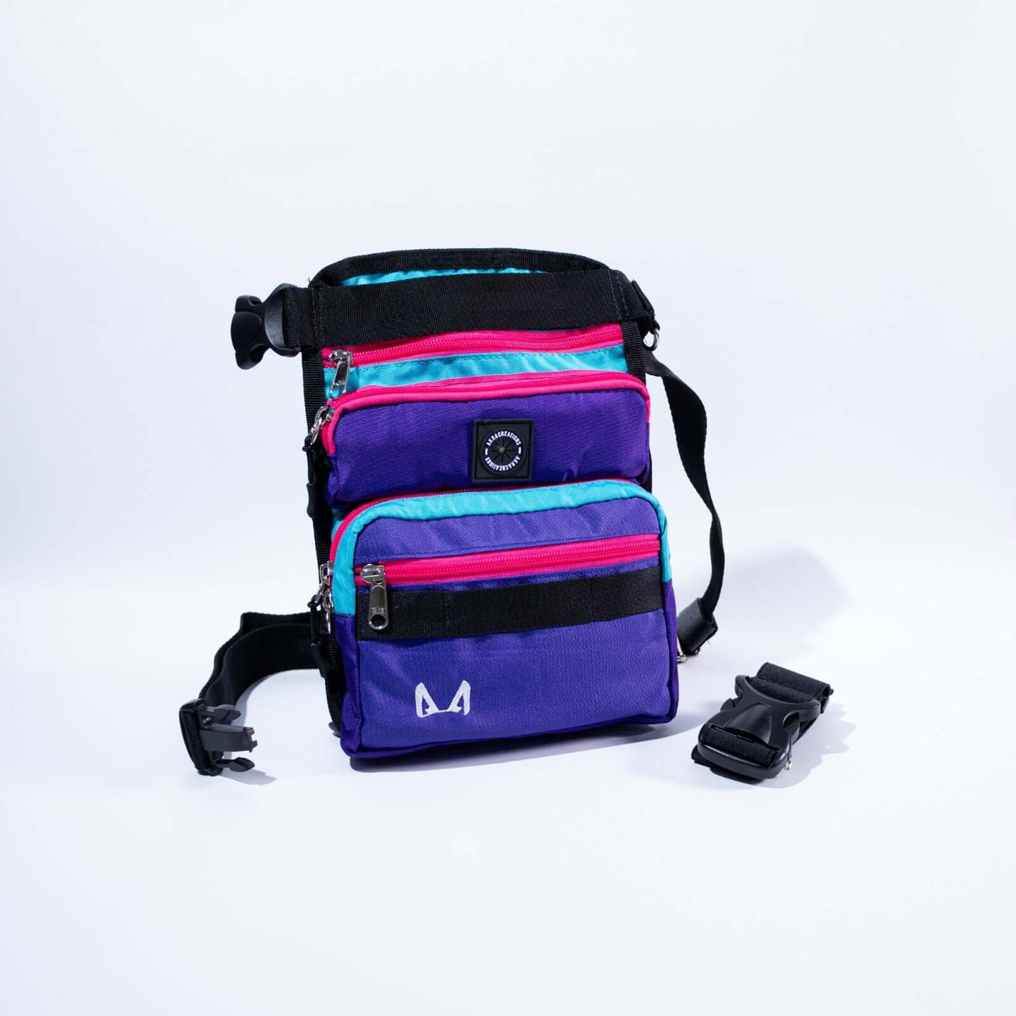 A purple and pink slim fit thigh treat bag with multiple compartments, including a main pocket, a small front compartment, and a back pocket. It features an adjustable waist strap, a removable elastic thigh strap, and is made from high-quality canvas fabric.