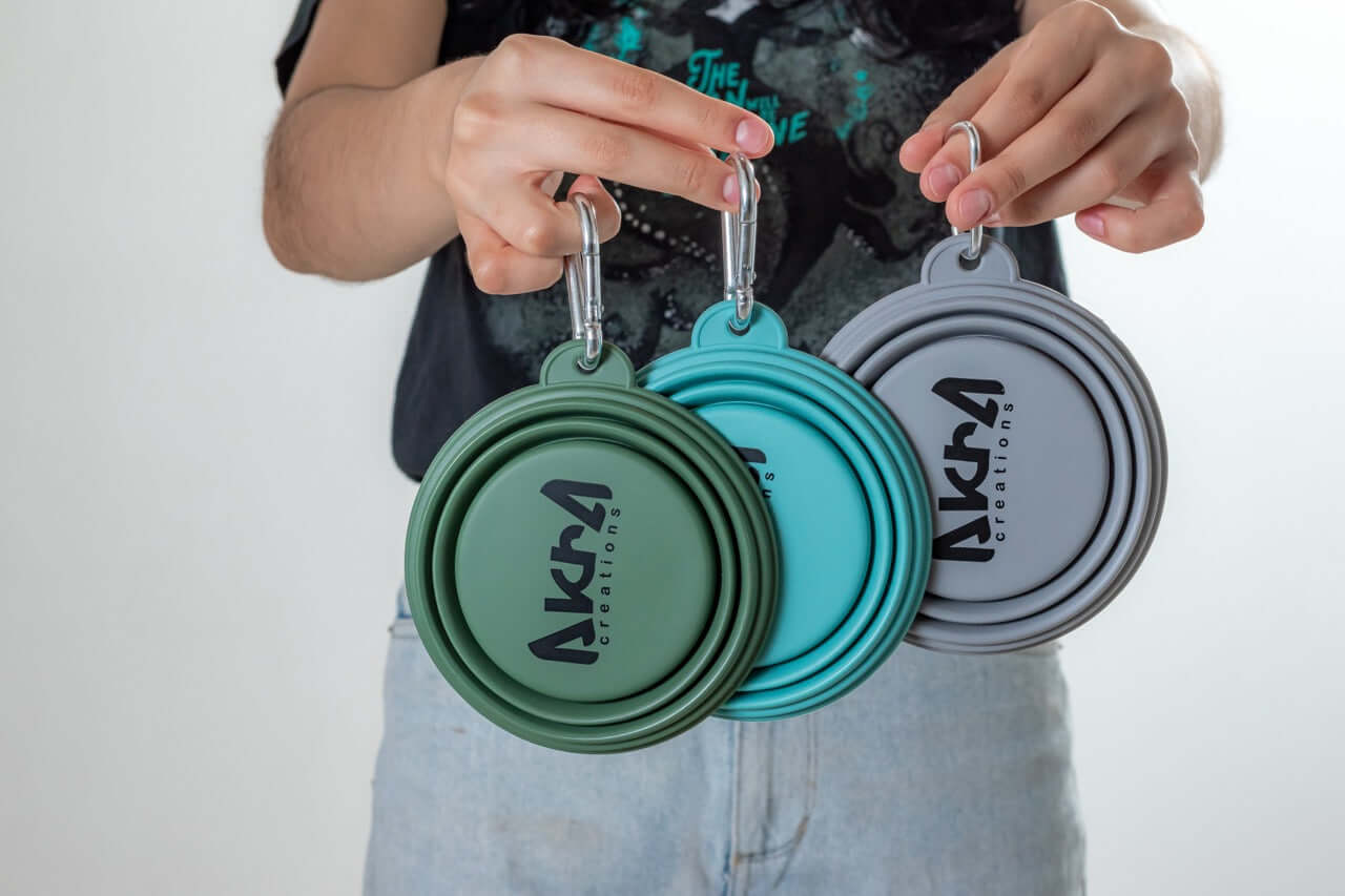 Three collapsible silicone lids with 'Akira' branding held by a person against a neutral background.