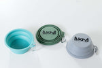 Set of three collapsible bowls in teal, green, and gray with 'AKMA' branding on a white background.