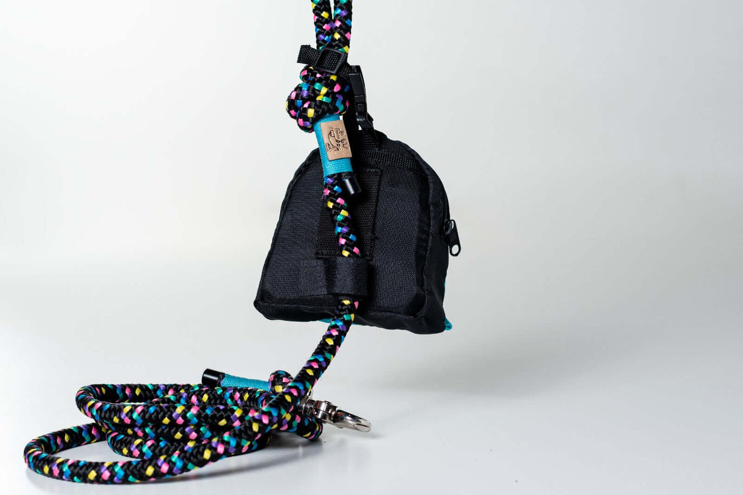 Black dog poop and treat bag holder attached to a colorful rope leash on a white background