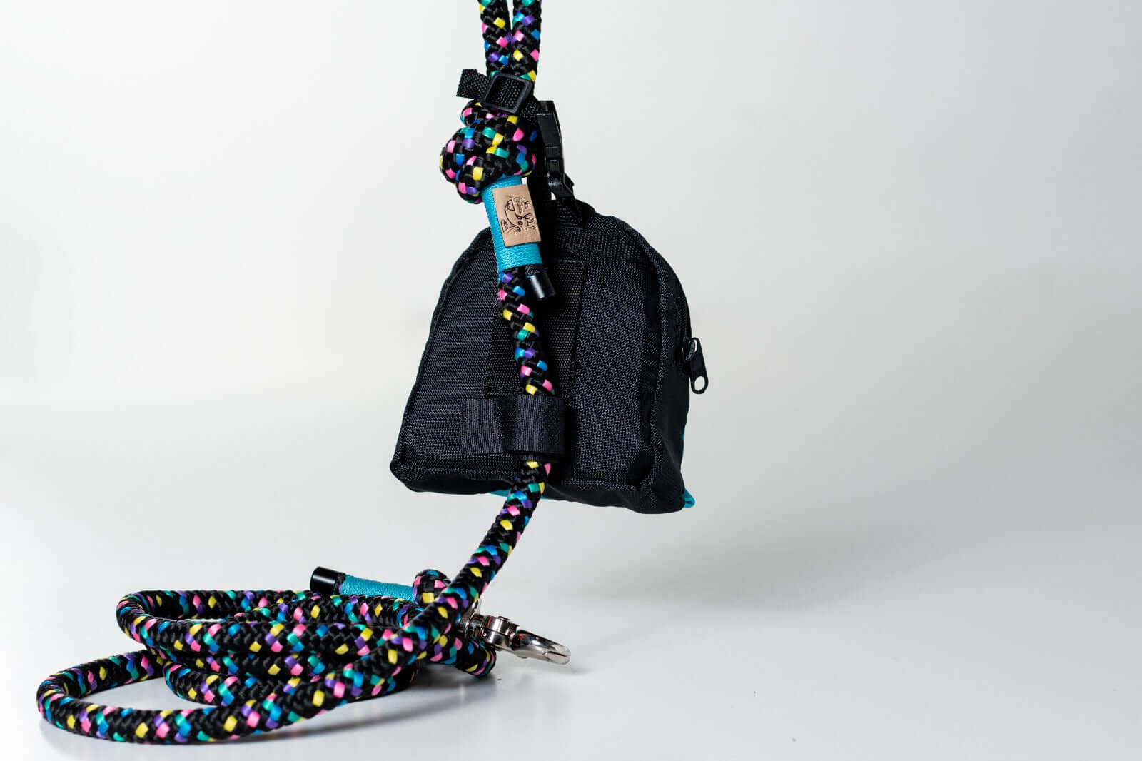 Black dog poop and treat bag holder attached to a colorful rope leash on a white background