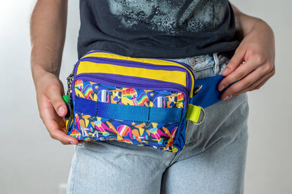 Person holding a pride/rainbow fanny pack with a plain background