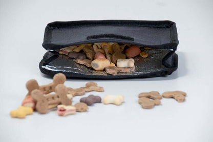 Black insulated dog treat bag with dog treats on a white background