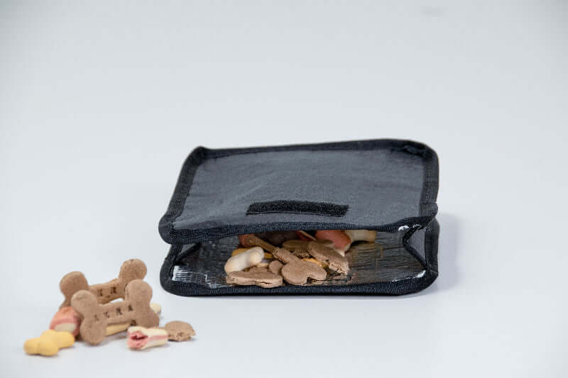 Insulated dog treat bag filled with dog treats on a white background