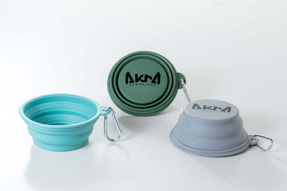 Three collapsible bowls in teal, green, and gray with 'AKUA' branding on a white background.